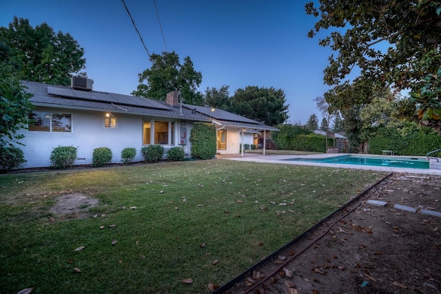 1463 W San Madele Ave, Fresno, CA 93711 - rear view of property with solar panels, a chimney, an outdoor pool, a yard, and stucco siding