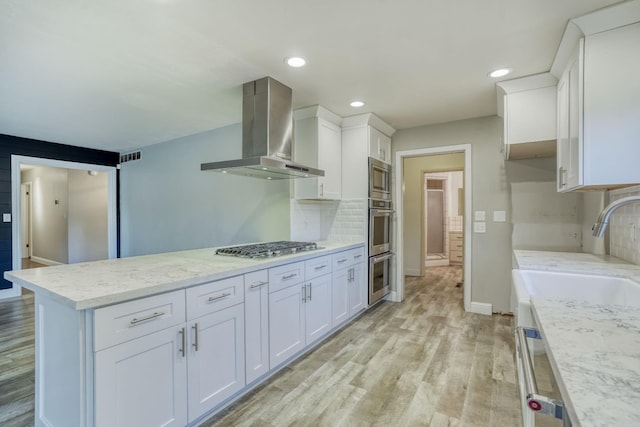 1463 W San Madele Ave, Fresno, CA 93711 - kitchen featuring wall chimney exhaust hood, stainless steel appliances, white cabinets, baseboards, and light wood finished floors