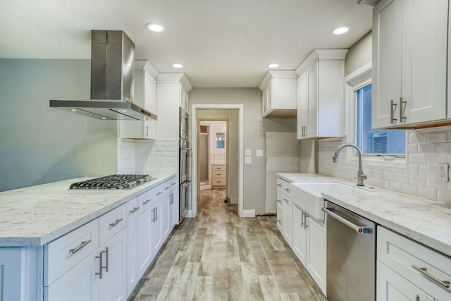 1463 W San Madele Ave, Fresno, CA 93711 - kitchen featuring wall chimney range hood, stainless steel appliances, white cabinetry, light wood-style flooring, and baseboards