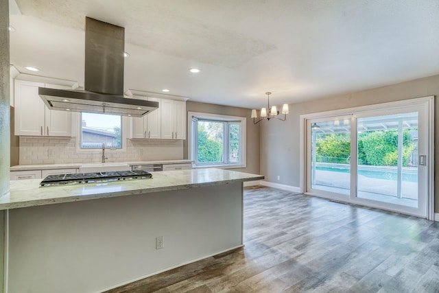 1463 W San Madele Ave, Fresno, CA 93711 - kitchen with island range hood, white cabinets, baseboards, light wood-type flooring, and a chandelier