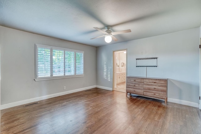 1463 W San Madele Ave, Fresno, CA 93711 - unfurnished bedroom with baseboards, wood finished floors, a ceiling fan, connected bathroom, and a textured ceiling