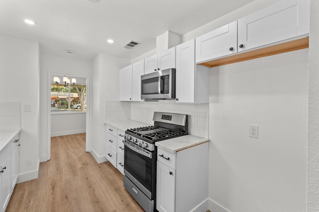 2543 E Ashcroft Ave, Fresno, CA 93726 - kitchen featuring stainless steel appliances, tasteful backsplash, light countertops, light wood finished floors, and white cabinetry