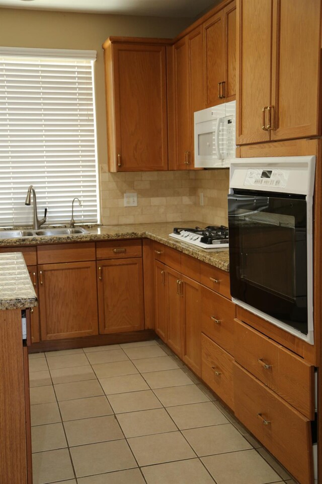 5811 W Cromwell Ave, Fresno, CA 93722 - kitchen featuring white appliances, a sink, light tile patterned floors, light stone counters, and decorative backsplash