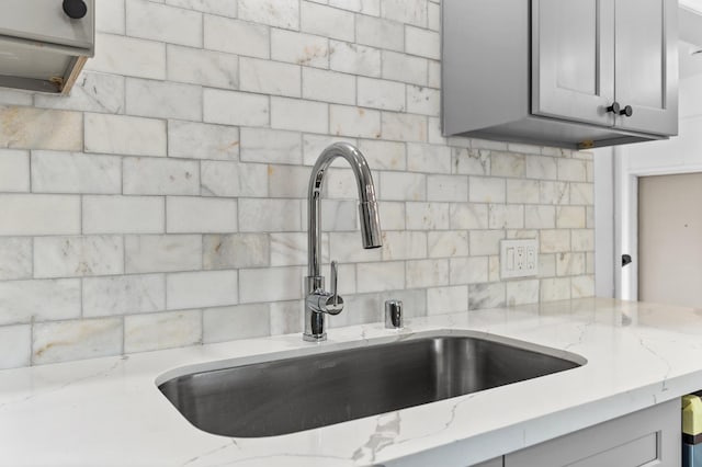 3926 N Kavanagh Ave, Fresno, CA 93705 - kitchen view of a sink, backsplash, light stone countertops, and gray cabinetry