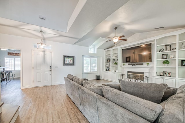 1039 N Burgan Ave, Clovis, CA 93611 - living area featuring light wood finished floors, vaulted ceiling, ceiling fan, a glass covered fireplace, and built in features