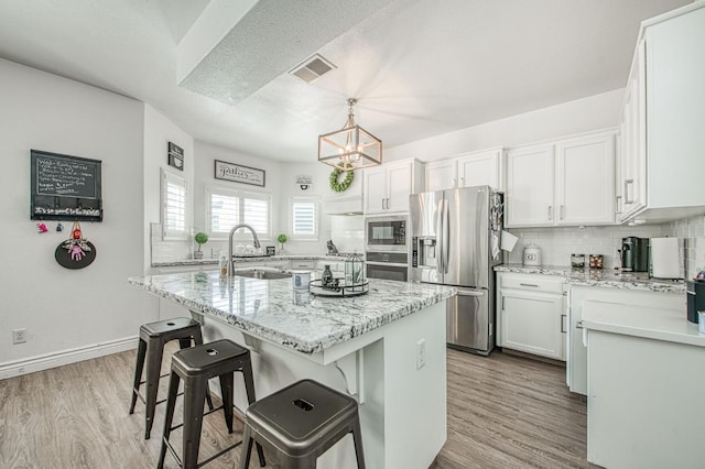 1039 N Burgan Ave, Clovis, CA 93611 - kitchen featuring appliances with stainless steel finishes, a sink, a chandelier, backsplash, and a center island with sink