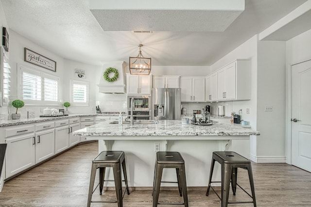 1039 N Burgan Ave, Clovis, CA 93611 - kitchen featuring stainless steel appliances, a sink, wood finished floors, tasteful backsplash, and a textured ceiling