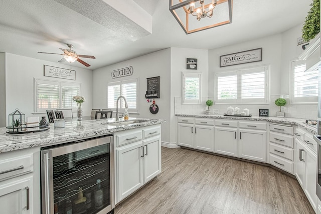 1039 N Burgan Ave, Clovis, CA 93611 - kitchen with beverage cooler, a sink, light wood-type flooring, white cabinetry, and a ceiling fan