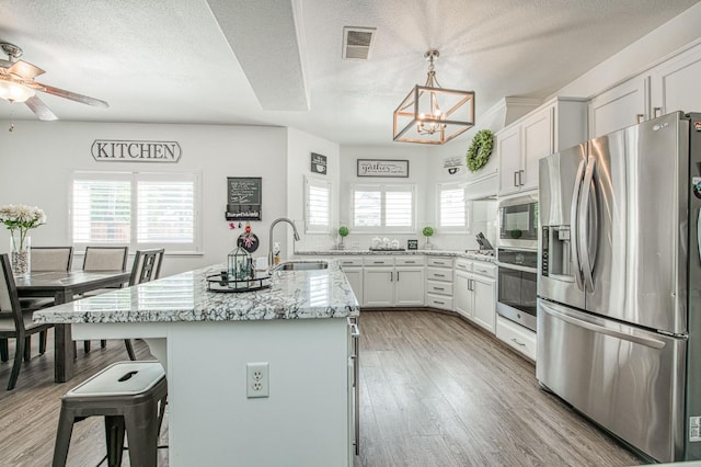 1039 N Burgan Ave, Clovis, CA 93611 - kitchen featuring appliances with stainless steel finishes, a textured ceiling, a chandelier, light stone counters, and a sink