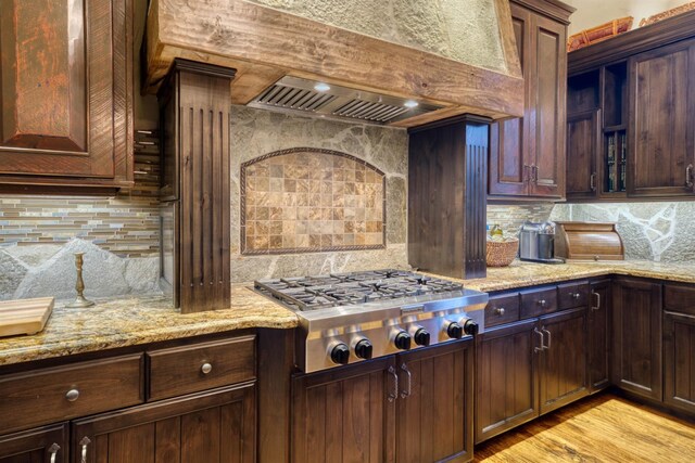 39516 Littleridge Rd, Shaver Lake, CA 93664 - kitchen with stainless steel gas cooktop, backsplash, custom exhaust hood, light stone countertops, and light wood-style flooring