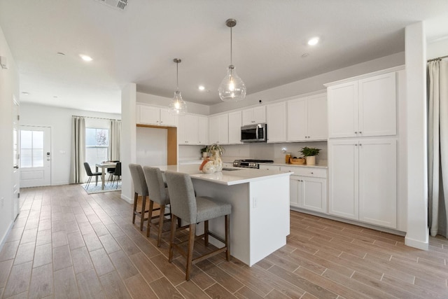 4433 N Phoenix, Fresno, CA 93723 - kitchen with stainless steel microwave, stove, light wood finished floors, recessed lighting, and white cabinets