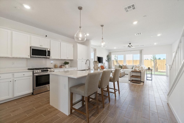 4433 N Phoenix, Fresno, CA 93723 - kitchen featuring stainless steel appliances, a sink, wood finished floors, a center island with sink, and a breakfast bar area