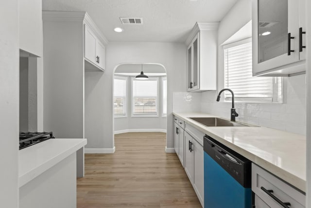kitchen featuring dishwashing machine, a sink, decorative backsplash, glass insert cabinets, and recessed lighting
