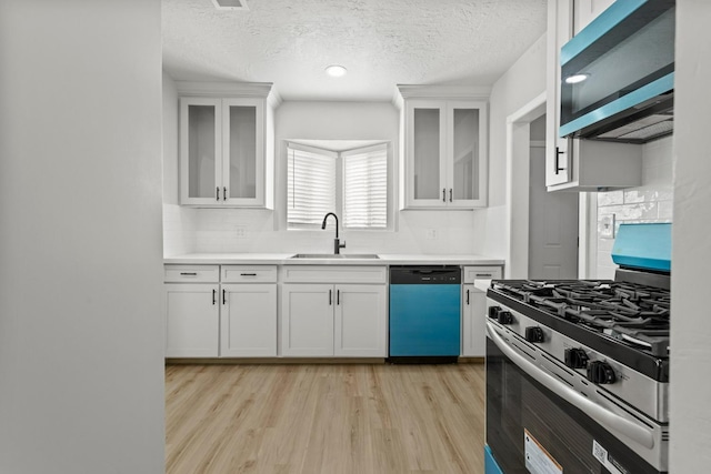 kitchen featuring stainless steel appliances, a sink, tasteful backsplash, light wood-style floors, and light countertops