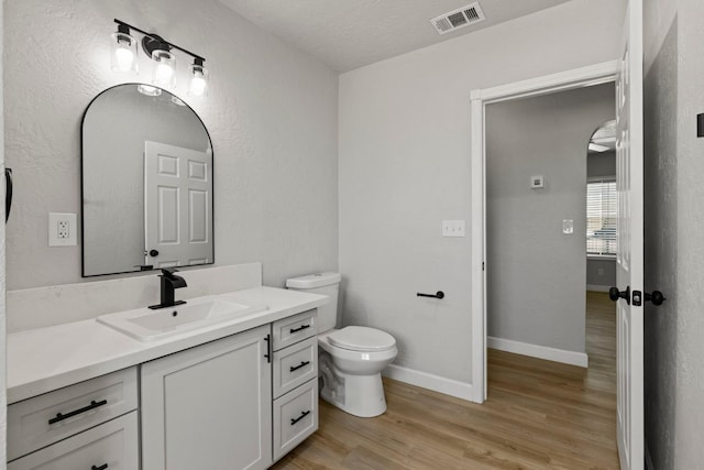 bathroom featuring toilet, vanity, wood finished floors, and baseboards