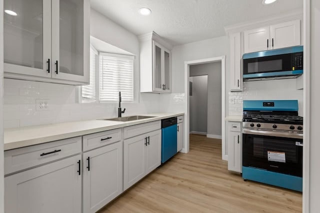 kitchen featuring stainless steel appliances, a sink, light countertops, white cabinets, and a textured ceiling