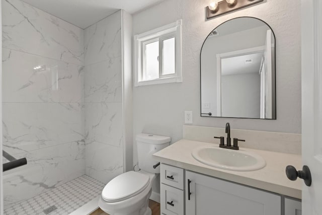 bathroom with vanity, toilet, and a marble finish shower