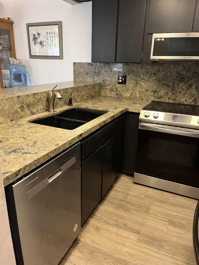 5455 N Marty Ave Unit 111, Fresno, CA 93711 - kitchen featuring stainless steel appliances, a sink, dark cabinetry, and light stone counters