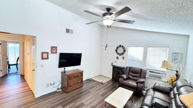 5455 N Marty Ave Unit 111, Fresno, CA 93711 - living room with a textured ceiling, wood finished floors, a ceiling fan, and high vaulted ceiling