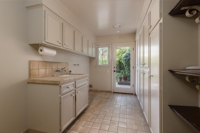 2331 W Celeste Ave, Fresno, CA 93711 - kitchen featuring a sink, tile counters, white cabinetry, and baseboards