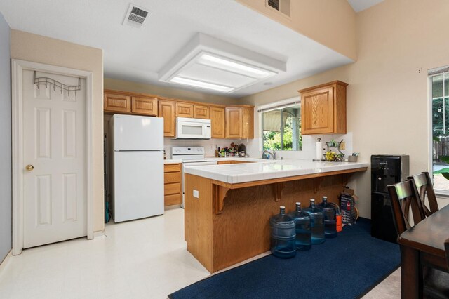 2173 Spruce, Clovis, CA 93611 - kitchen with white appliances, a peninsula, a breakfast bar, tile countertops, and a sink