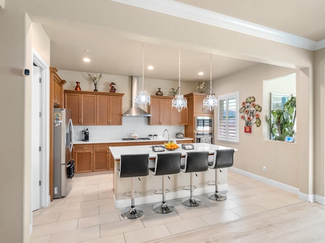 2127 Chennault Ave, Clovis, CA 93611 - kitchen with wall chimney range hood, appliances with stainless steel finishes, light countertops, an island with sink, and a breakfast bar