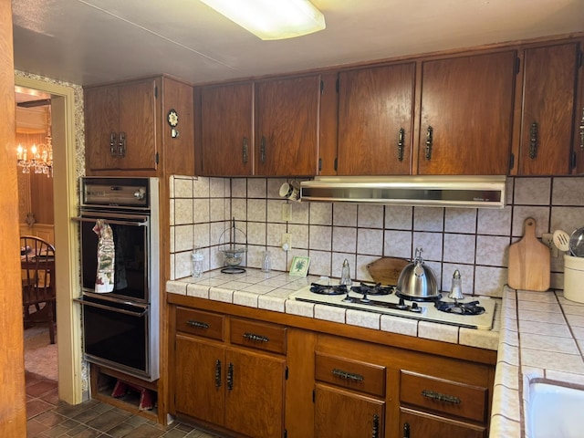 32101 E Trimmer Springs Rd, Sanger, CA 93657 - kitchen featuring under cabinet range hood, a chandelier, white gas cooktop, tasteful backsplash, and tile counters