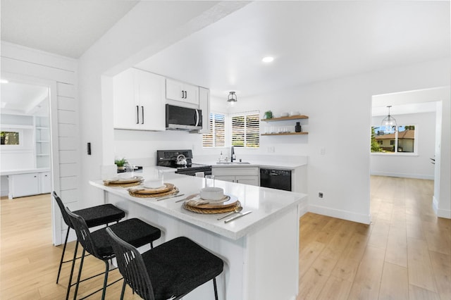 4561 N Price Ave, Fresno, CA 93726 - kitchen with black appliances, a sink, light countertops, a kitchen bar, and plenty of natural light