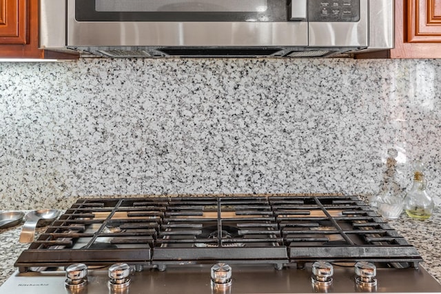 3615 W Sunnyview Ave NW, Visalia, CA 93291 - detailed view of stainless steel gas cooktop, backsplash, and brown cabinetry