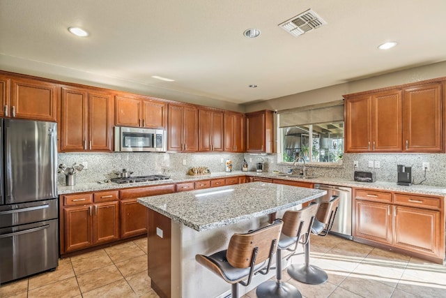 3615 W Sunnyview Ave NW, Visalia, CA 93291 - kitchen with appliances with stainless steel finishes, a sink, light tile patterned flooring, brown cabinets, and light stone counters