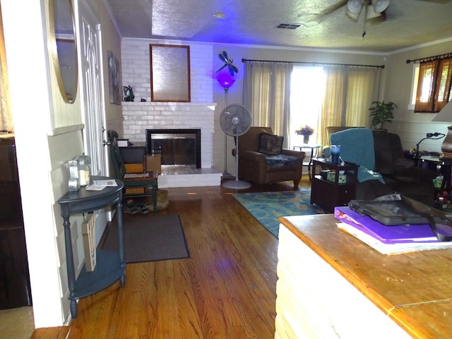 4457 E Brown Ave, Fresno, CA 93703 - living room with wood finished floors, a brick fireplace, ceiling fan, ornamental molding, and a textured ceiling
