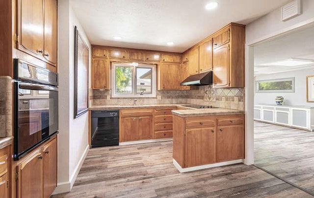 6224 N 3rd St, Fresno, CA 93710 - kitchen with black appliances, under cabinet range hood, decorative backsplash, light wood-style floors, and brown cabinets