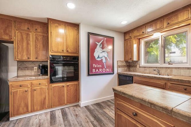6224 N 3rd St, Fresno, CA 93710 - kitchen with black appliances, tile countertops, brown cabinetry, backsplash, and recessed lighting