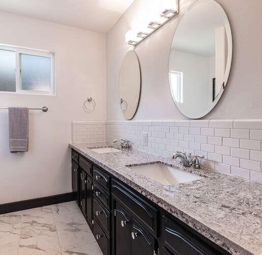 6224 N 3rd St, Fresno, CA 93710 - bathroom featuring double vanity, marble look tiles, and backsplash