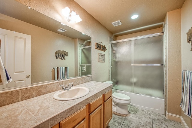 40753 Wild Iris Ln, Shaver Lake, CA 93664 - full bathroom featuring a textured wall, vanity, toilet, combined bath / shower with glass door, and tile patterned floors