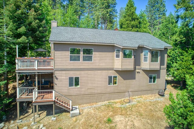 40753 Wild Iris Ln, Shaver Lake, CA 93664 - back of property with a wooden deck, a chimney, stairs, roof with shingles, and view of scattered trees