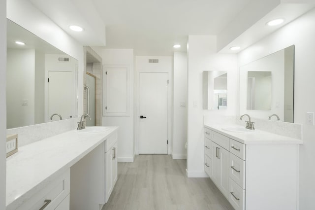 5610 N Arthur Ave, Fresno, CA 93711 - full bathroom featuring two vanities, recessed lighting, a stall shower, and wood finished floors