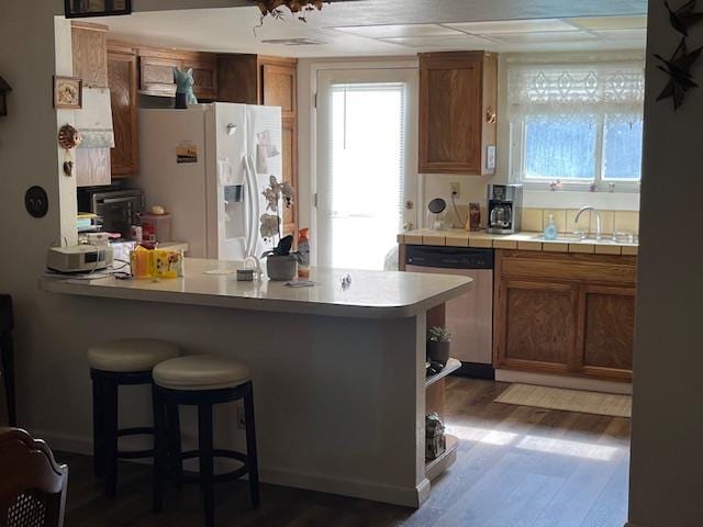 1173 Menlo Ave, Clovis, CA 93612 - kitchen featuring dishwasher, white refrigerator with ice dispenser, a kitchen bar, and plenty of natural light