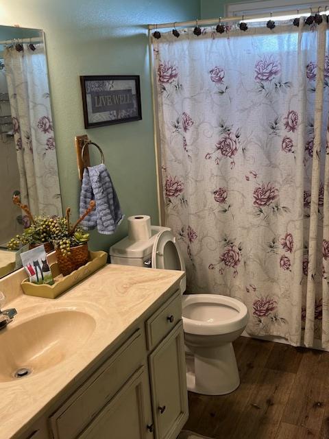 1173 Menlo Ave, Clovis, CA 93612 - full bathroom featuring hardwood / wood-style flooring, vanity, toilet, and a shower with curtain