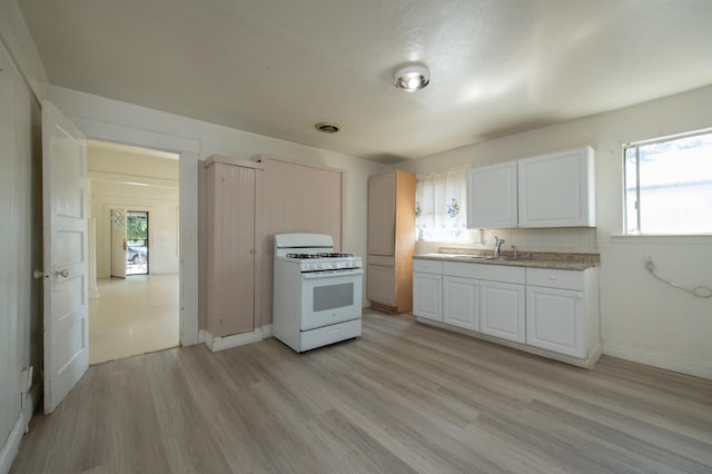 208 N 5th St, Fowler, CA 93625 - kitchen with white range with gas stovetop, light wood finished floors, white cabinetry, light countertops, and baseboards