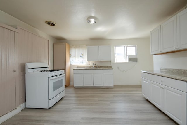208 N 5th St, Fowler, CA 93625 - kitchen featuring white range with gas cooktop, white cabinetry, and light wood-style flooring