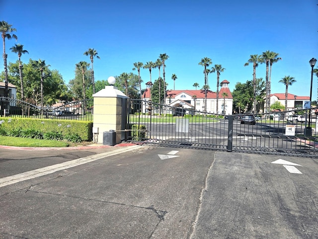 8147 N Cedar Ave Unit 115, Fresno, CA 93720 - view of asphalt road with a gate, a gated entry, curbs, and street lights