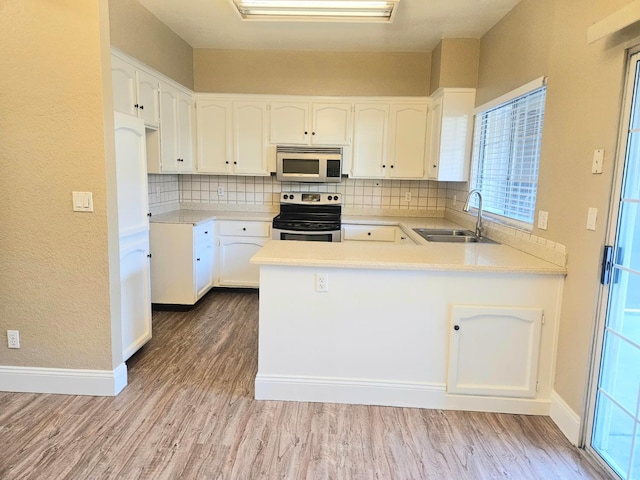 8147 N Cedar Ave Unit 115, Fresno, CA 93720 - kitchen with stainless steel electric stove, a sink, tasteful backsplash, a peninsula, and wood finished floors