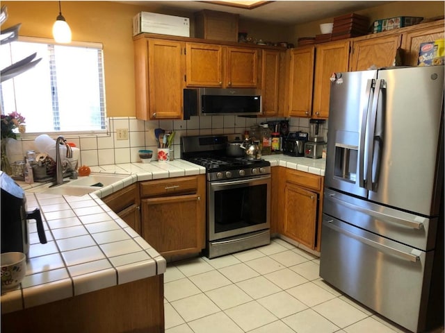 3546 N Berlin Ave, Fresno, CA 93722 - kitchen featuring appliances with stainless steel finishes, tile counters, a sink, and brown cabinets
