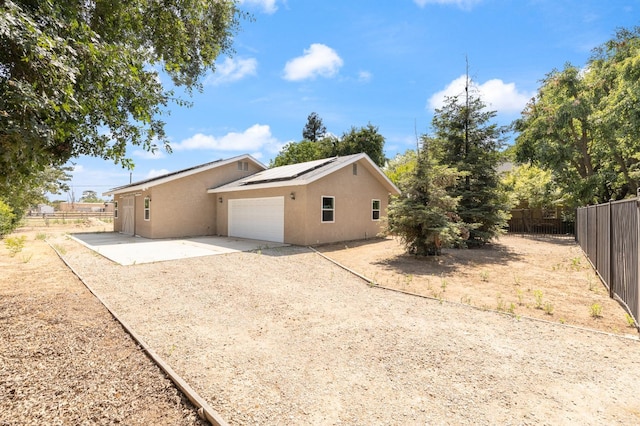 8741 E Los Altos Ave, Clovis, CA 93619 - view of side of property featuring stucco siding, concrete driveway, roof mounted solar panels, a patio area, and a garage