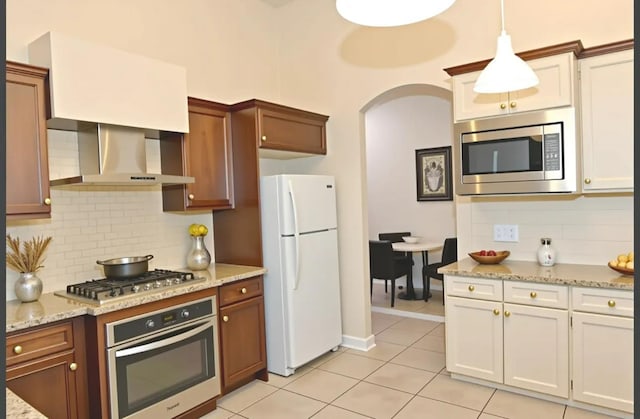7285 W San Jose Ave, Fresno, CA 93723 - kitchen featuring appliances with stainless steel finishes, wall chimney exhaust hood, backsplash, light tile patterned floors, and pendant lighting
