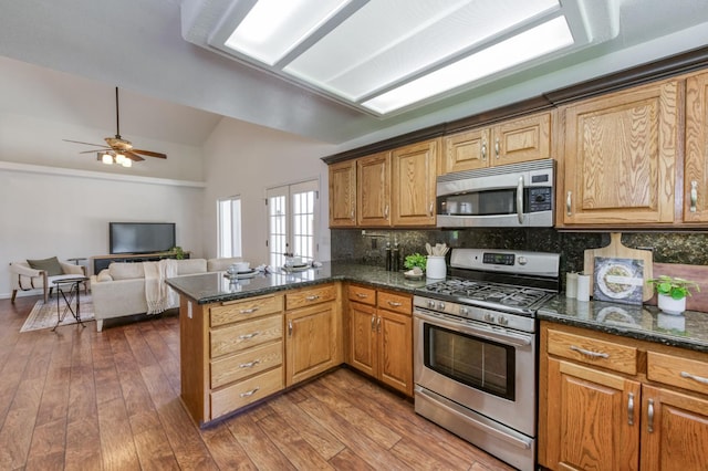 770 N Cherry Ln, Clovis, CA 93611 - kitchen with stainless steel appliances, lofted ceiling, a peninsula, decorative backsplash, and dark wood-style flooring