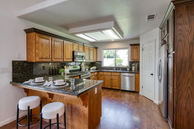 770 N Cherry Ln, Clovis, CA 93611 - kitchen featuring stainless steel appliances, a sink, a peninsula, backsplash, and brown cabinetry