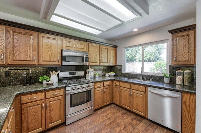 770 N Cherry Ln, Clovis, CA 93611 - kitchen featuring stainless steel appliances, a sink, decorative backsplash, brown cabinetry, and dark wood-type flooring