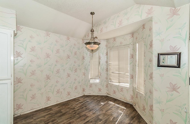 7543 N Spalding Ave, Fresno, CA 93720 - unfurnished dining area featuring dark wood-style floors, wallpapered walls, lofted ceiling, and a textured ceiling